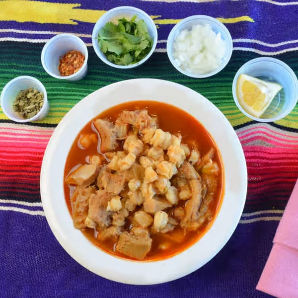 Menudo soup with hominy, tripe, and red chili broth, served with cilantro, onions, and lemon.