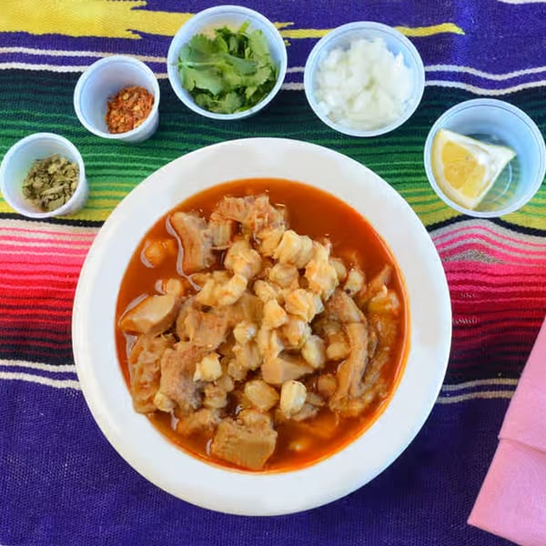 Menudo soup with hominy and tripe, served with sides of cilantro, onions, chili flakes, oregano, and lemon.
