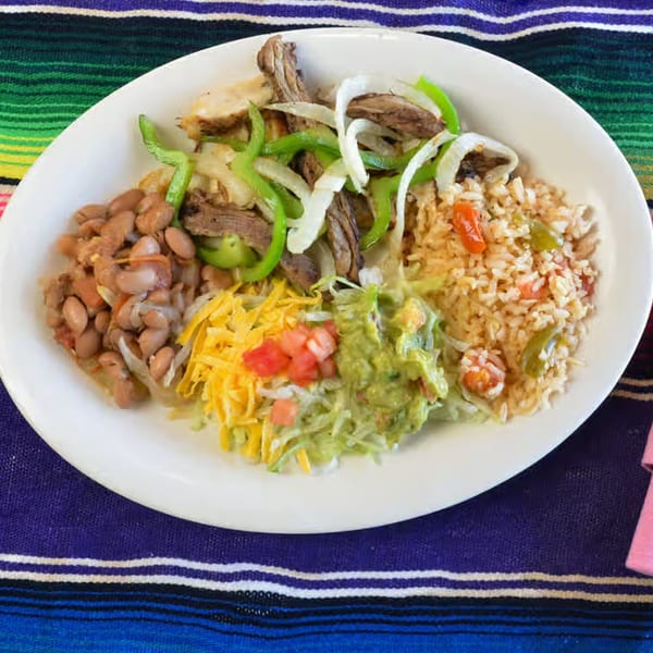 A La Casita Mexican Grill fajita plate with steak, chicken, rice, beans, guacamole, and cheese.