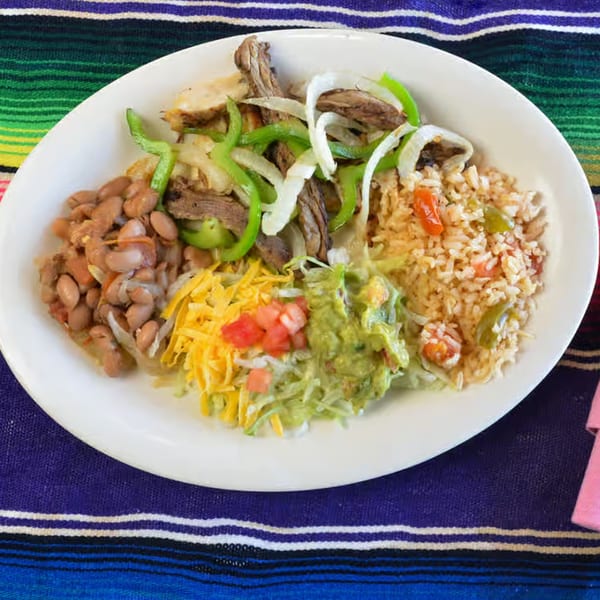 La Casita Mexican Grill's fajita plate with steak, rice, beans, guacamole, cheese, and pico de gallo.
