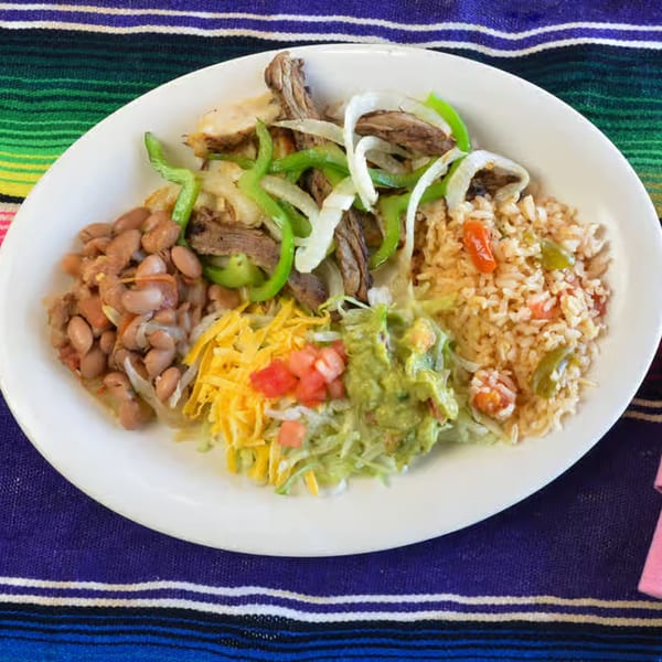 A La Casita Mexican Grill plate with fajita meat, rice, beans, guacamole, and shredded cheese.