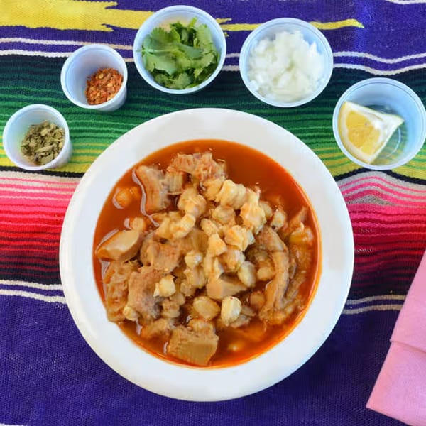 Menudo soup with hominy and tripe, served with sides of cilantro, onions, chili flakes, and lemon.