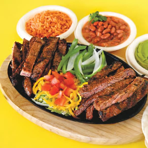 Sizzling La Casita Mexican Grill fajitas with steak, peppers, onions, rice, beans, and guacamole.